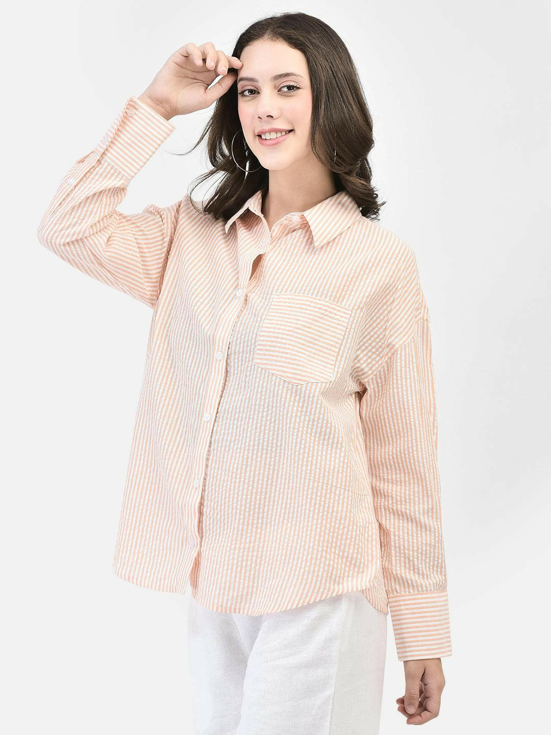 Alt Text: Model wearing elvtd. peach striped button-up shirt with white pants. Image Description: A model wearing an elvtd. peach striped button-up shirt paired with white pants. The stylish and casual outfit is perfect for warm weather and various occasions.