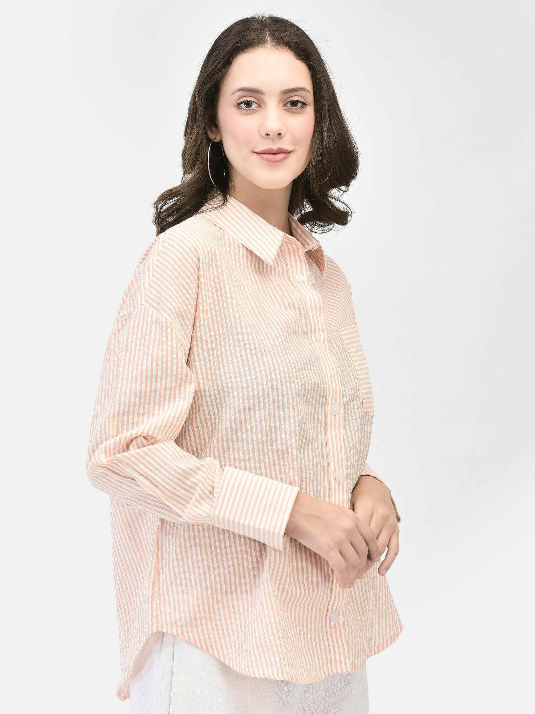 Alt Text: Model wearing elvtd. peach striped button-up shirt with white pants. Image Description: "A model wearing an elvtd. peach striped button-up shirt paired with white pants. The stylish and casual outfit is perfect for warm weather and various occasions.