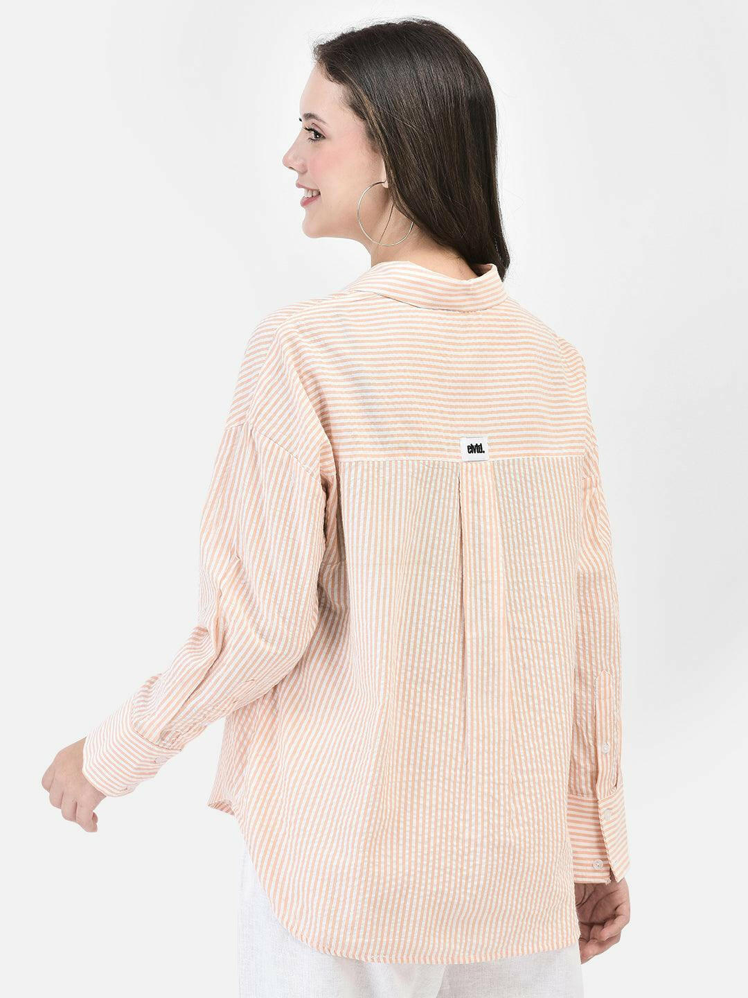 Alt Text: Model wearing elvtd. peach striped button-up shirt with white pants. Image Description: A model wearing an elvtd. peach striped button-up shirt paired with white pants. The stylish and casual outfit is perfect for warm weather and various occasions.