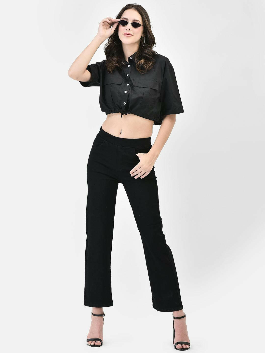 Front view of model wearing black cropped shirt with wide-leg black trousers and sunglasses