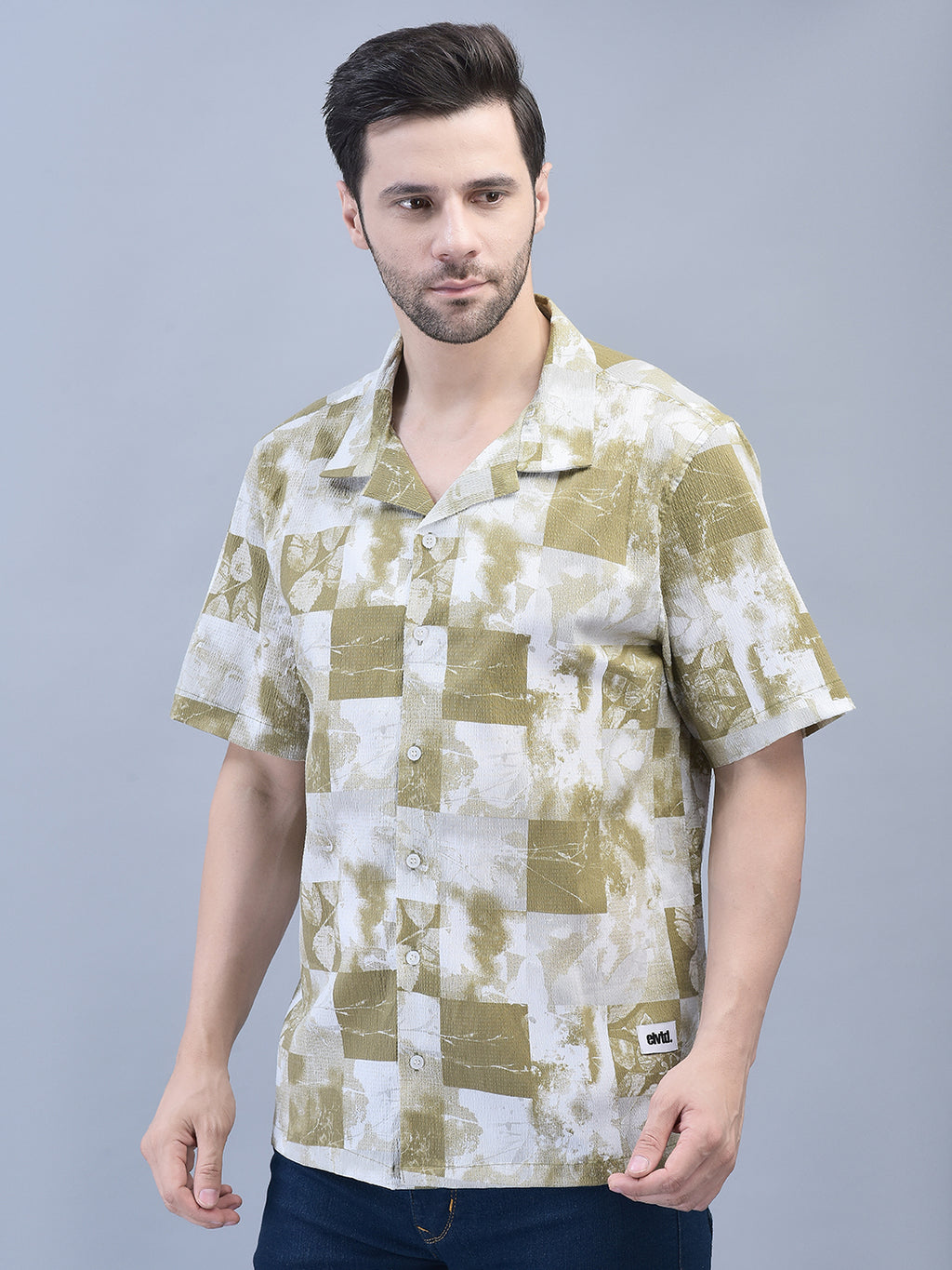 A male model wearing a green, blue, and white checkered shirt with short sleeves and a crew neck.