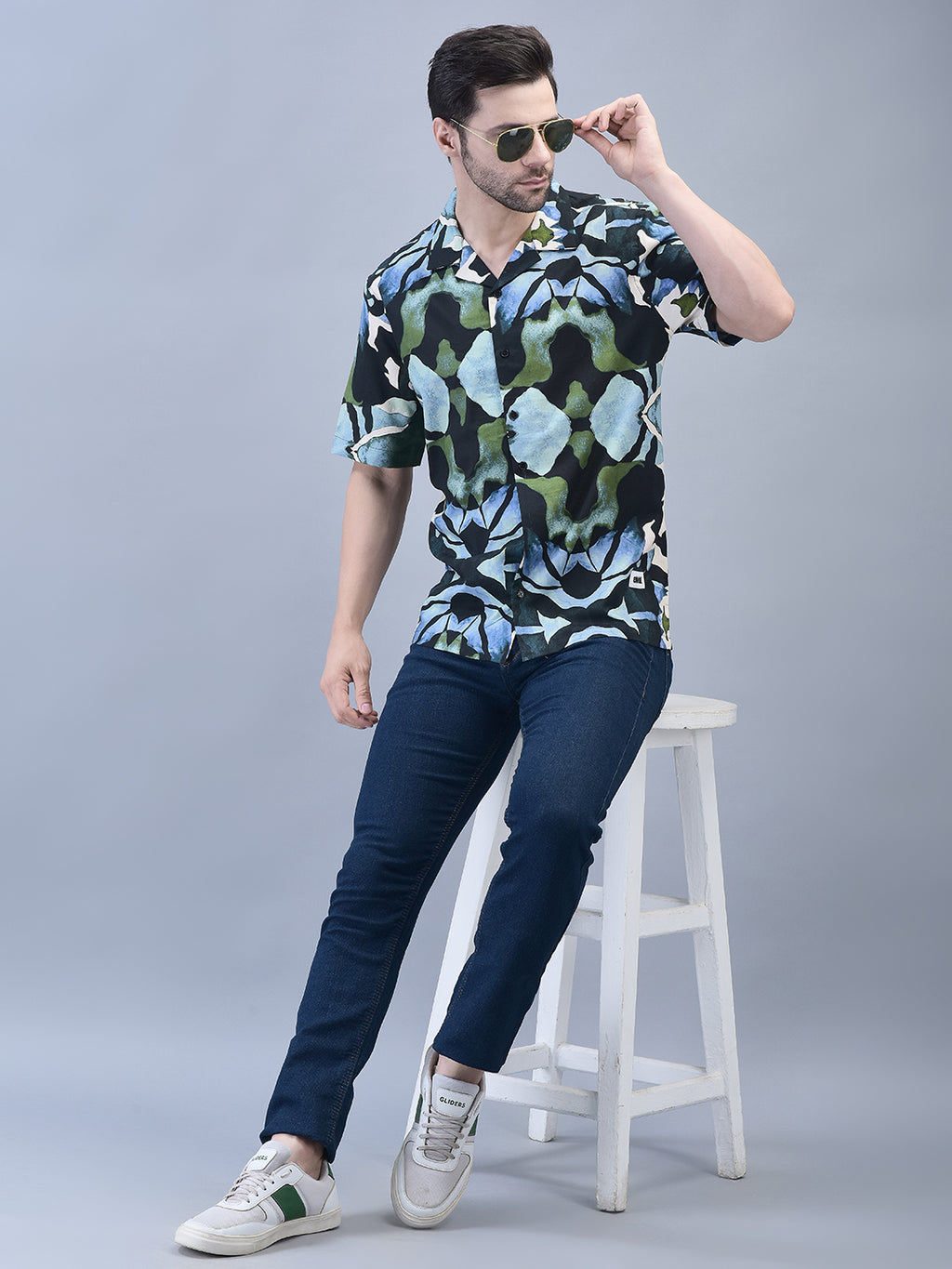 Man posing seated with one hand raised – oversized graphic cotton shirt styling