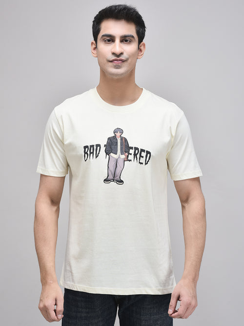 A male model wearing a beige t-shirt with a graphic print in the center, standing against a plain background.