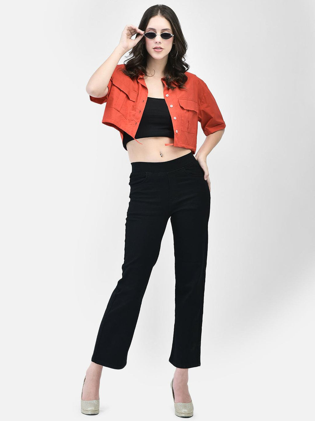 Woman posing in a red cropped cotton shirt with black pants and heels – front view