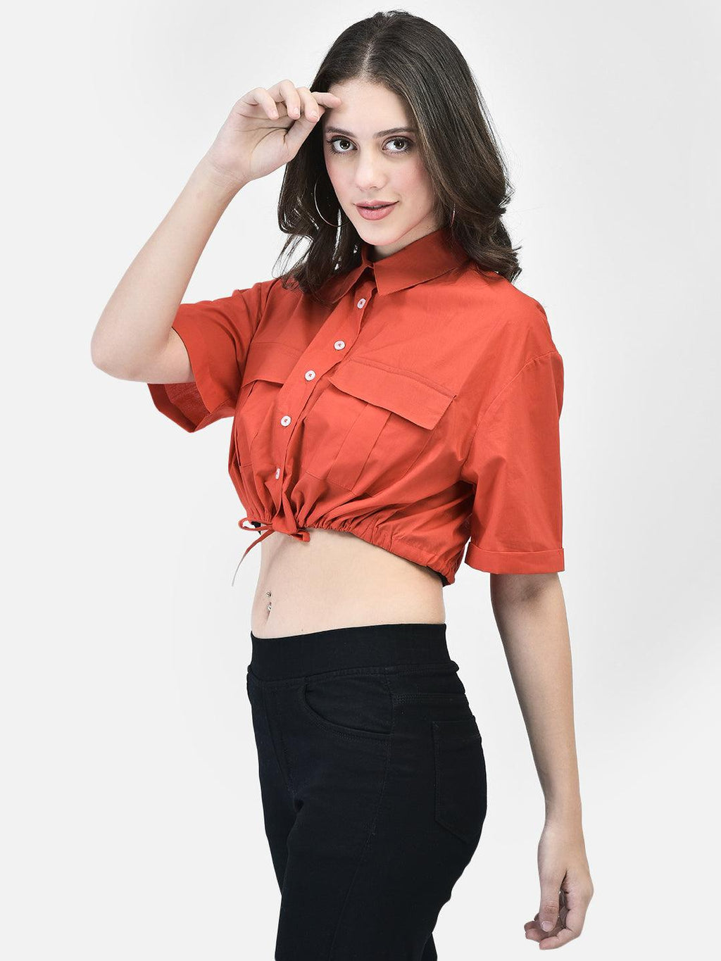 Side pose of woman adjusting sunglasses while styling red cropped shirt