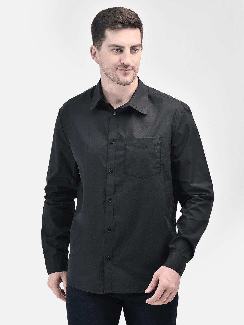 Male model standing in black button-down shirt with hands in pocket